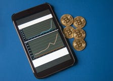 Few gold bitcoins lie on the table in front of and next to the tablet on which charts of Bitcoins cost growth are visible. Royalty Free Stock Photos Few gold bitcoins lie on the table in front of and next to the tablet on which charts of Bitcoins cost growth are visible. Royalty Free Stock Photos