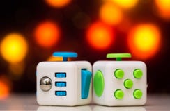 Fidget cube anti stress toy. Detail of finger play toy used for relax. Gadget placed on colorful bokeh background royalty free stock photography Fidget cube anti stress toy. Detail of finger play toy used for relax. Gadget placed on colorful bokeh background royalty free stock photography