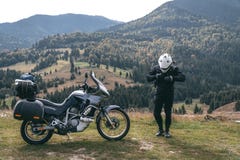 Fietsermens met zijn toeristische motorfiets, met grote zakken klaar voor een lange reis, zwarte stijl, witte helm, rit, avontuur royalty-vrije stock foto's Fietsermens met zijn toeristische motorfiets, met grote zakken klaar voor een lange reis, zwarte stijl, witte helm, rit, avontuur royalty-vrije stock foto's