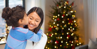Figlia felice che bacia sua madre su natale fotografie stock libere da diritti Figlia felice che bacia sua madre su natale fotografie stock libere da diritti