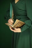 Figura hermosa de la mujer en el vestido verde oscuro de 50 ` s que sostiene el libro del vintage Imágenes de archivo libres de regalías Figura hermosa de la mujer en el vestido verde oscuro de 50 ` s que sostiene el libro del vintage Imágenes de archivo libres de regalías