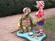 Figures of famous characters of Russian fairy tale, wooden Buratino and old turtle in city park Stock Image Figures of famous characters of Russian fairy tale, wooden Buratino and old turtle in city park Stock Image