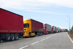 Fila dos caminhões que passam os caminhões da fronteira internacional, os vermelhos e os diferentes das cores no engarrafamento n foto de stock Fila dos caminhões que passam os caminhões da fronteira internacional, os vermelhos e os diferentes das cores no engarrafamento n foto de stock