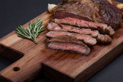 Filete asado a la parrilla del ribeye del primer de mármol de la carne de vaca con las especias en un tablero de madera Medio jug foto de archivo Filete asado a la parrilla del ribeye del primer de mármol de la carne de vaca con las especias en un tablero de madera Medio jug foto de archivo
