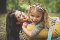 A filha que senta-se nas mães dobra, jogando com mamã foto de stock A filha que senta-se nas mães dobra, jogando com mamã foto de stock