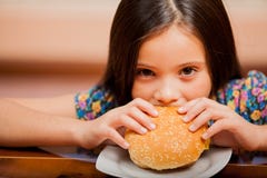 Fille affamée mangeant un hamburger photographie stock Fille affamée mangeant un hamburger photographie stock