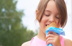 Fille assez petite mangeant léchant la grande crème glacée dans rire heureux de cône de gaufres sur le fond de nature photos stock Fille assez petite mangeant léchant la grande crème glacée dans rire heureux de cône de gaufres sur le fond de nature photos stock