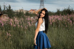 Fille aux cheveux longs dans le domaine vert avec des fleurs photo libre de droits Fille aux cheveux longs dans le domaine vert avec des fleurs photo libre de droits