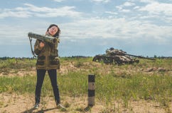 Fille dans l'uniforme militaire et des jeans avec un bazooka dans des ses mains Photo libre de droits Fille dans l'uniforme militaire et des jeans avec un bazooka dans des ses mains Photo libre de droits