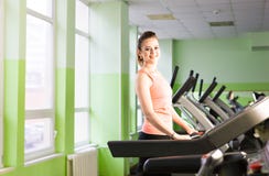 Fille de forme physique courant sur le tapis roulant Femme avec les jambes musculaires dans le gymnase photo libre de droits Fille de forme physique courant sur le tapis roulant Femme avec les jambes musculaires dans le gymnase photo libre de droits