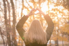 Fille faisant la forme de coeur avec ses mains dehors au coucher du soleil photo stock Fille faisant la forme de coeur avec ses mains dehors au coucher du soleil photo stock