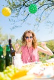 Fille ?g?e de l'adolescence dans la chemise ? carreaux rouge se reposant par la table sur le jardin image libre de droits Fille ?g?e de l'adolescence dans la chemise ? carreaux rouge se reposant par la table sur le jardin image libre de droits