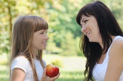 Fille heureuse et sa mère ayant l'amusement sur le pique-nique dans le parc au su image stock Fille heureuse et sa mère ayant l'amusement sur le pique-nique dans le parc au su image stock