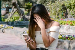 Fille inquiétée d'adolescent de hippie regardant son téléphone intelligent en parc image stock Fille inquiétée d'adolescent de hippie regardant son téléphone intelligent en parc image stock
