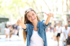 Fille joyeuse faisant des gestes des pouces dans la rue photos stock Fille joyeuse faisant des gestes des pouces dans la rue photos stock