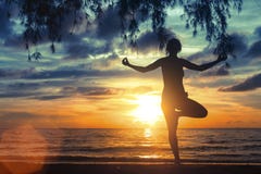Fille méditant sur la plage de mer pendant un coucher du soleil merveilleux Yoga et forme physique images stock Fille méditant sur la plage de mer pendant un coucher du soleil merveilleux Yoga et forme physique images stock