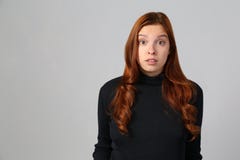 Fille rousse étonnée sur le fond gris photo stock Fille rousse étonnée sur le fond gris photo stock