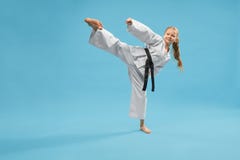 Fille sportive active dans le kimono donnant un coup de pied avec la jambe dans le studio photos libres de droits Fille sportive active dans le kimono donnant un coup de pied avec la jambe dans le studio photos libres de droits