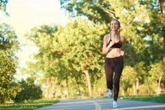Fille sportive courant le long du champ de courses en parc de ville images stock Fille sportive courant le long du champ de courses en parc de ville images stock