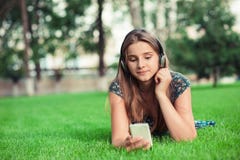 Fille écoutant de la musique regardant intéressée le message téléphonique qu'elle a reçu photo stock Fille écoutant de la musique regardant intéressée le message téléphonique qu'elle a reçu photo stock