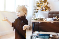 Fille étonnée par enfant en bas âge mignon dans le salon L'arbre de Noël est sur le fond image stock Fille étonnée par enfant en bas âge mignon dans le salon L'arbre de Noël est sur le fond image stock