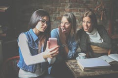 Filles d'étudiants ayant la conversation et à l'aide du téléphone intelligent image stock Filles d'étudiants ayant la conversation et à l'aide du téléphone intelligent image stock