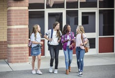 Filles de l'adolescence quittant l'école parlant et marchant ensemble image libre de droits Filles de l'adolescence quittant l'école parlant et marchant ensemble image libre de droits
