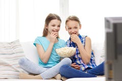 Filles heureuses avec le maïs éclaté regardant la TV à la maison photo stock Filles heureuses avec le maïs éclaté regardant la TV à la maison photo stock