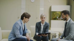 A filtração disparou da mulher de negócios com a tabuleta digital que duscussing com os colegas masculinos do negócio que sentam- vídeos de arquivo A filtração disparou da mulher de negócios com a tabuleta digital que duscussing com os colegas masculinos do negócio que sentam- vídeos de arquivo