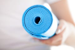 Fin : tapis bleu plié de pilates chez des mains de la femme images stock Fin : tapis bleu plié de pilates chez des mains de la femme images stock