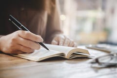 Fine sulle mani femminili che scrivono sul taccuino al caffè fotografia stock libera da diritti Fine sulle mani femminili che scrivono sul taccuino al caffè fotografia stock libera da diritti