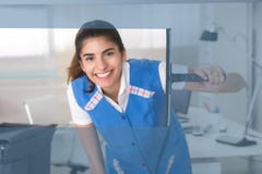 Finestra di vetro di pulizia sorridente della lavoratrice con il seccatoio fotografia stock Finestra di vetro di pulizia sorridente della lavoratrice con il seccatoio fotografia stock