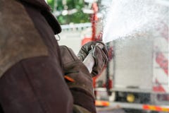 Fireman Spraying Water During Practice. Cropped image of fireman spraying water during practice at fire station Stock Images Fireman Spraying Water During Practice. Cropped image of fireman spraying water during practice at fire station Stock Images