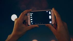 The fireworks are being recorded on the smartphone. Two hands are holding the smartphone, which is recording fireworks The fireworks are being recorded on the smartphone. Two hands are holding the smartphone, which is recording fireworks