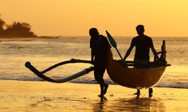 Fisherman boat with two fishers at Bali, Indonesia during sunset at the beach.