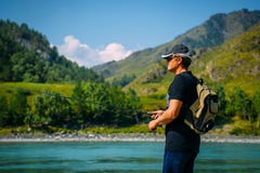 Fisherman on the mountain river at the nice summer day. Trout fly fishing in the mountain river with mountains in background royalty free stock photo Fisherman on the mountain river at the nice summer day. Trout fly fishing in the mountain river with mountains in background royalty free stock photo