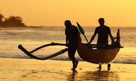 Fiskarefartyg med två fishers på Bali, Indonesien under solnedgång på stranden royaltyfria foton Fiskarefartyg med två fishers på Bali, Indonesien under solnedgång på stranden royaltyfria foton