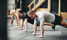 Fit people doing pushups together during a gym exercise class