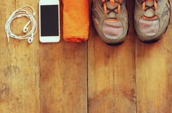 Fitness concept with mobile phone with earphones, towel and sport footwear over wooden background Royalty Free Stock Photography Fitness concept with mobile phone with earphones, towel and sport footwear over wooden background Royalty Free Stock Photography