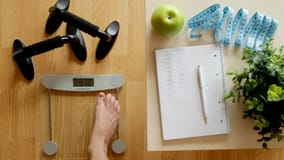 Fitness and weight loss concept, scale and notebook on a wooden table