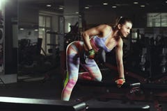 Fitness young girl in the gym doing exercises with dumbbells