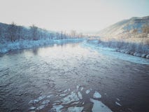 Fiume con ghiaccio su un fondo delle montagne immagini stock Fiume con ghiaccio su un fondo delle montagne immagini stock