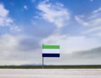 Flag of Sierra Leone with vast meadow and blue sky behind it. royalty free stock photography Flag of Sierra Leone with vast meadow and blue sky behind it. royalty free stock photography