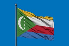 Flaga Comoros macha w wiatrze przeciw głębokiemu niebieskiemu niebu ilustracji Flaga Comoros macha w wiatrze przeciw głębokiemu niebieskiemu niebu ilustracji