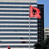 Flaga państowowa Albania przeciw tłu nowożytny hotel w kapitale Tirana fotografia stock Flaga państowowa Albania przeciw tłu nowożytny hotel w kapitale Tirana fotografia stock