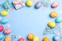 Flat lay composition with Easter eggs, present and flowers on color background, space for text