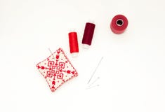 Flat lay with handmade red embroidered needle pad, thread spools, pins, needles, mock up, top view. Layout mockup on blank white stock photos Flat lay with handmade red embroidered needle pad, thread spools, pins, needles, mock up, top view. Layout mockup on blank white stock photos