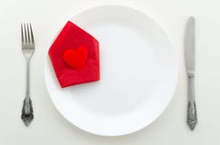 Flat lay romantic dinner proposal concept. Dish with cutlery and heart on a red napkin with with background stock photo Flat lay romantic dinner proposal concept. Dish with cutlery and heart on a red napkin with with background stock photo