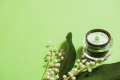 fleurs cosmétiques de crème et du muguet sur un fond vert photos libres de droits fleurs cosmétiques de crème et du muguet sur un fond vert photos libres de droits