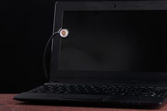LED USB lamp connected to laptop and peeking from behind the monitor. Concept of alive usb-lamp. Black background stock image LED USB lamp connected to laptop and peeking from behind the monitor. Concept of alive usb-lamp. Black background stock image